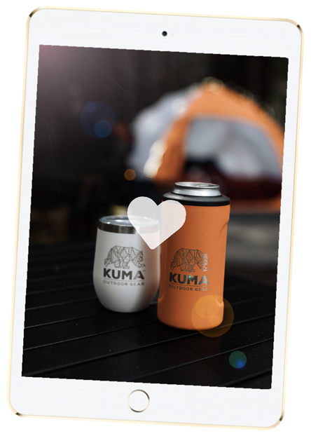 iPad with golden back and white front with screen showing two Kuma products one short white tumbler and one large orange can holder sleeve both on dark picnic table with large heart icon in front